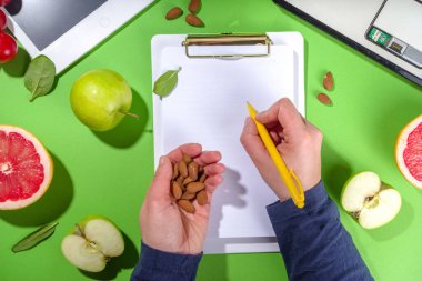 Yemek diyet planı konsepti, not defterinde, sağlıklı yiyecek meyveleri, sebzeler, tablet, not defterleri ve parlak yeşil masa arkaplanını sümüklendirmek için aksesuarlar ile