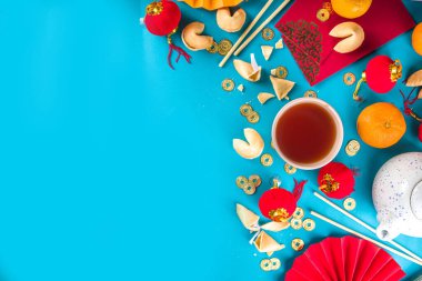 Çin 'in yeni yıl geçmişi. Geleneksel Çin Yeni Yıl dekoruna sahip kırmızı ve sarı düz yatak, dileklerle dolu zarflar, altın sikkeler, yelpazeler, Çin fenerleri, portakallar ve çay.