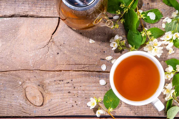 Herbal jasmin flower tea. Jasmine green tea in  glass teapot and white tea cup, with fresh jasmin blossom