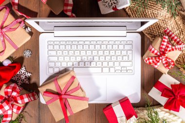 Üzerinde Noel hediyesi kutuları olan dizüstü bilgisayar tahta arka planda. Hediyeli defter, köknar ağacı ve kış dekoru. Noel ve Yeni Yıl için Hazırlık
