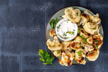 Kızarmış karnabahar, çedar peyniri krem soslu ve otlu, sebze sonbahar vejetaryen yemeği, arka planda hafif kaplamalı fotokopi alanı. 