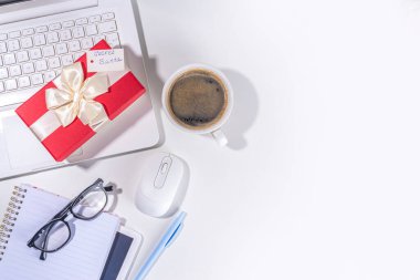 İş yerindeki gizli Noel Baba 'dan hediye. Ofis Noel ve Yeni Yıl kutlama oyunu. Ofis masası yüzeyi, neşeli hediye kutusu olan defter, beyaz arkaplan düz kopya alanı