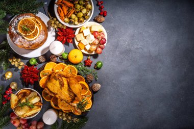 Noel ya da Yeni Yıl yemeği karanlık masada. Geleneksel Xmas parti yemekleri - pannetone, fırında tavuk, sebze, patates, peynir ve meyve tabağı, üst görünüm fotokopi alanı