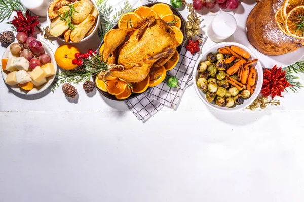 白い木製のテーブルの上でクリスマスや新年のディナーフード 伝統的なクリスマスパーティー料理のセット パンネ 焼きチキン ポテト チーズ フルーツプレート トップビューコピースペース — ストック写真