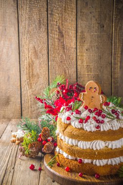 Noel pastası, çırpılmış krem peynirli zencefilli kek, dekore edilmiş kızılcık ve zencefilli kurabiye, Noel dekorlu ahşap arka plan.