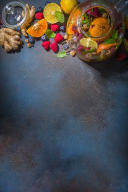 Çaydanlıkta meyve ve çilek çayı. Limonlu, naneli, yabanmersinli, zencefilli, portakallı, elmalı sıcak içecek. Koyu mavi arkaplan fotokopi alanında sıcak aromalı buhar içeceği  