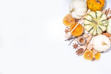 Sonbahar mevsimi balkabağı baharat pişirme ve içecekleri içme. Çeşitli renkli balkabakları, fındıklar, beyaz arka planda mevsimlik baharatlar. Balkabağı turtası, latte, sonbahar Şükran Günü için kurabiyeler.