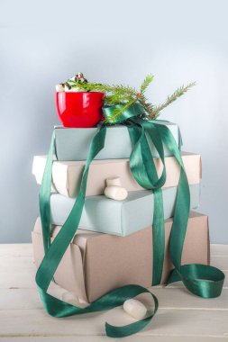 Sıcak çikolatalı büyük bir Noel hediyesi yığını, kaide gibi üstünde kalın, rahat pastel renkli el işi kağıt kutular içinde yeşil şenlikli Xmas kurdelesi, bir fincan marşmelovlu kakao, fotokopi alanı