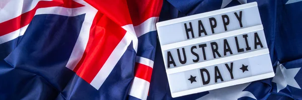 Australia Day greeting card Background with  australian flag, silver stars, lightbox with text Happy Australia day, paper red, blue, white decor, over blue background copy space