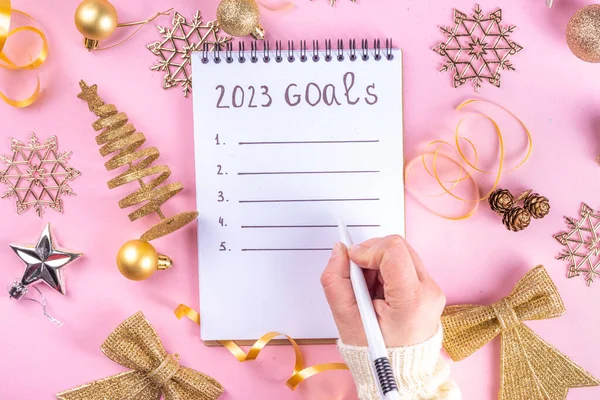 Notebook with New\'s Year Resolutions massage, with Christmas ornaments and decor. New Year goals List 2023, plan listing of new year beginnings goals and resolutions setting. Flat lay copy space