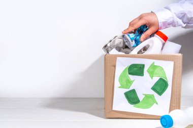 Çöp ayıklama, atık geri dönüşüm konsepti. Geri dönüşüm malzemelerinin olduğu kutu - plastik, cam, kağıt, karton, beyaz ahşap arka plan fotokopi alanı. Kadın elleri çeşitli çöp ve çöpleri ayırıyor.