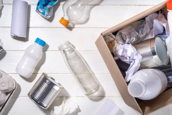 ゴミの分別 廃棄物のリサイクルの概念 プラスチック ガラス 段ボール 白い木製の背景コピースペース 様々なゴミやゴミを分別する女の手 — ストック写真