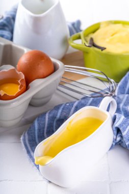 Malzemeli ev yapımı krema. Vanilya, süt ve yumurta. Tatlı krema beyaz mutfak masasının fotokopi masasında tatlı pişirme arkaplanı. 