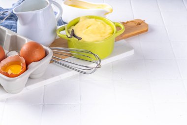 Malzemeli ev yapımı krema. Vanilya, süt ve yumurta. Tatlı krema beyaz mutfak masasının fotokopi masasında tatlı pişirme arkaplanı. 