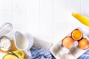 Malzemeli ev yapımı krema. Vanilya, süt ve yumurta. Tatlı krema beyaz mutfak masasının fotokopi masasında tatlı pişirme arkaplanı. 