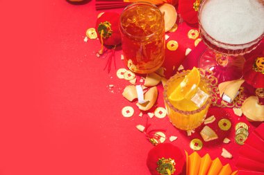 Çin Yeni Yıl Kokteyli içecekleri, üç farklı bardakta, çeşitli kırmızı altın rengi alkollü parti içecekleri, geleneksel Çin Yeni Yıl dekoru, karşılama zarfları, Çin fenerleri, bozuk paralar.