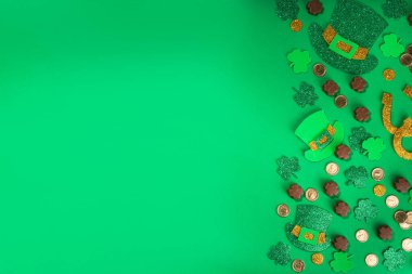 Aziz Patrick düz arka planı yonca yaprakları, leprikon şapka dekoru, altın sikkeler ve Aziz Patrik Günü sembolü olarak çikolatalar.