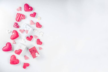 Sevgililer Günü arkaplanı, el yapımı kırmızı tekstil kalpleri, tatlı kalp şeklinde şekerlemeler ve hediye kutuları. Beyaz arkaplan yüzme deseni üst görünüm kopyalama alanı