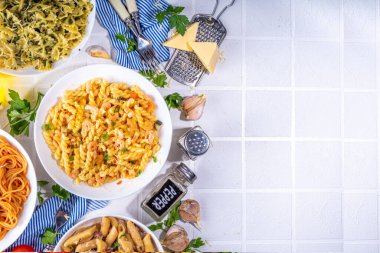 Beyaz fayanslı arka planda farklı soslu makarna seti. Spagetti, farfalle, makarna, deniz ürünleri, ıspanak, karbonara, domates soslu fusilli makarna. İtalyan yemeği, Akdeniz yemeği konsepti