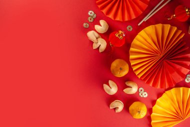 Çin 'in yeni yıl geçmişi. Geleneksel Çin Yeni Yıl dekoruna sahip kırmızı ve sarı düz yatak, dileklerle dolu zarflar, altın sikkeler, yelpazeler, Çin fenerleri, portakallar ve çay.