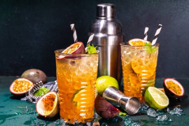 Tutku meyveli, limonlu ve naneli renkli tropikal kokteyl. Uzun alkollü tutku meyveli içecek. Arka planda koyu renk fotokopi alanı.