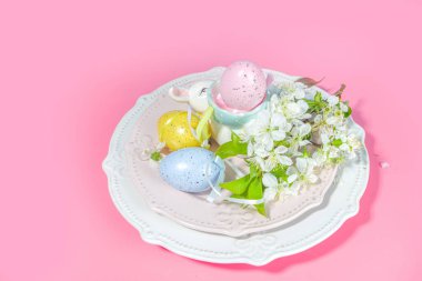 Paskalya sofrası dekorasyonu, renkli Paskalya yumurtaları, bahar bahçesi çiçekleri, tavşancık dekoru, yüksek renkli pembe arka plan fotokopi alanı.