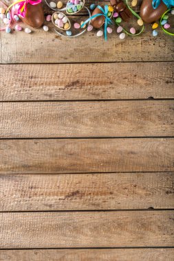 Paskalya kartı geçmişi. Çikolatalı Paskalya yumurtaları ve ahşap arka planda kurdeleli ve fiyonklu tavşanlar.