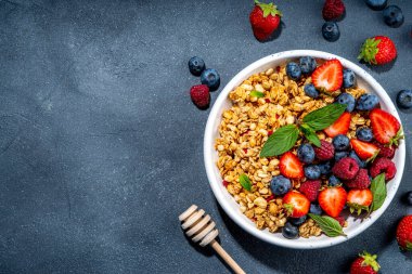 Healthy breakfast granola with fresh berry - strawberry, raspberry, blueberry on black background