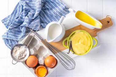 Malzemeli ev yapımı krema. Vanilya, süt ve yumurta. Tatlı krema beyaz mutfak masasının fotokopi masasında tatlı pişirme arkaplanı. 