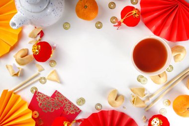 Çin 'in yeni yıl geçmişi. Geleneksel Çin Yeni Yıl dekoruna sahip kırmızı ve sarı düz yatak, dileklerle dolu zarflar, altın sikkeler, yelpazeler, Çin fenerleri, portakallar ve çay.