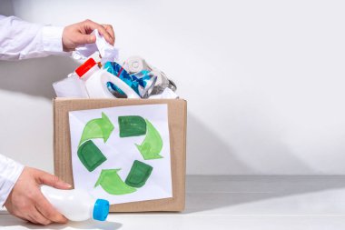 Çöp ayıklama, atık geri dönüşüm konsepti. Geri dönüşüm malzemelerinin olduğu kutu - plastik, cam, kağıt, karton, beyaz ahşap arka plan fotokopi alanı. Kadın elleri çeşitli çöp ve çöpleri ayırıyor.