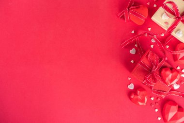 Sevgililer Günü tebrik kartı arkaplanı, hediye kutusu şenlik kurdeleleri, kırmızı masa arkaplanındaki çeşitli kalpler, metin için üst görünüm fotokopi alanı. Sevgililer Günü konsepti.