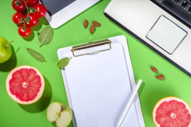 Yemek diyet planı konsepti, not defterinde, sağlıklı yiyecek meyveleri, sebzeler, tablet, not defterleri ve parlak yeşil masa arkaplanını sümüklendirmek için aksesuarlar ile