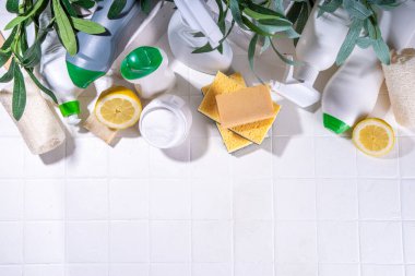 Çevre dostu organik temizlik konsepti. Çevre dostu temizlik aletleri - eko fırçalar, aletler süngerler, doğal temizlik ürünleri, soda, sabun, limon, sirke, beyaz arka planda yeşil yapraklı şişeler