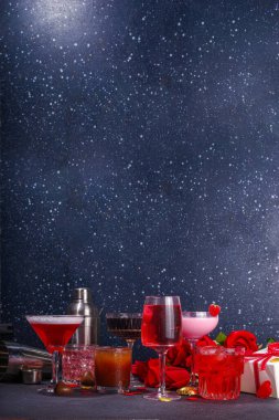 Valentine day romantic bar background. Set various red, pink, chocolate alcohol drinks for Valentine day party or dating, in different cocktail glasses with rose flower bouquet, heart decor, gift box