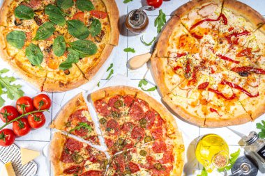 Evde ya da restoranda servis edilen üç çeşit pizza. İçinde pişirme malzemeleri, domates, fesleğen, ıspanak, roka klasik pepperoni pizza, vejetaryen sebze ve deniz ürünleri karidesli pizza var., 