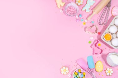 Cute pink sweet baking flat lay for Easter holiday. Cooking background with baking ingredients, rolling pin, whisk for whipping, cookie and cutters, sugar sprinkling, flour, top view copy space 