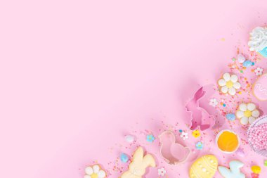 Cute pink sweet baking flat lay for Easter holiday. Cooking background with baking ingredients, rolling pin, whisk for whipping, cookie and cutters, sugar sprinkling, flour, top view copy space 