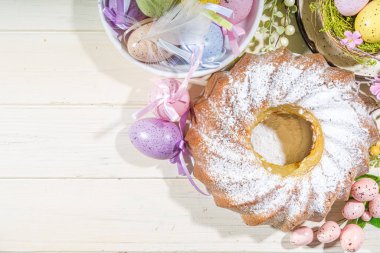 Geleneksel bahar bayramı pudra şekerli paskalya pastası. Hafif ahşap arka planda güneş ışığı, Paskalya yumurtaları, dekor ve bahar dalları