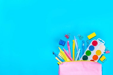 Back to school flatlay background. Pink pencil case with various school stationery on high-colored bright background