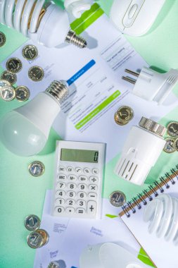 Modern modernleşme teknolojisi ve cihazlarıyla enerji tasarrufu. Elektrik faturaları, LED ampuller, ısı termostatı, açık yeşil masa fotokopi alanındaki hesap makinesi. Yeşil olsun, enerji maliyetleri kavramı