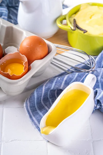 Malzemeli ev yapımı krema. Vanilya, süt ve yumurta. Tatlı krema beyaz mutfak masasının fotokopi masasında tatlı pişirme arkaplanı. 