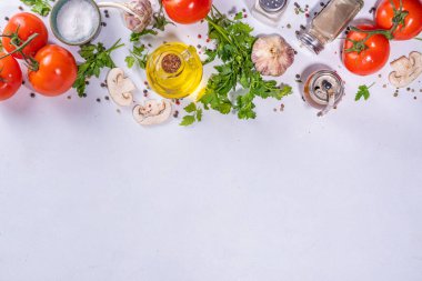 Cooking background with vegetable ingredients. Healthy dinner preparation flat lay, with fresh raw tomatoes, onion, garlic, herbs and greens, olive oil, salt, pepper seasonings, on white background 