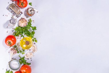Cooking background with vegetable ingredients. Healthy dinner preparation flat lay, with fresh raw tomatoes, onion, garlic, herbs and greens, olive oil, salt, pepper seasonings, on white background 