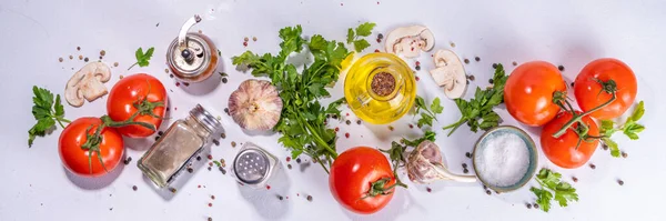 Cooking background with vegetable ingredients. Healthy dinner preparation flat lay, with fresh raw tomatoes, onion, garlic, herbs and greens, olive oil, salt, pepper seasonings, on white background