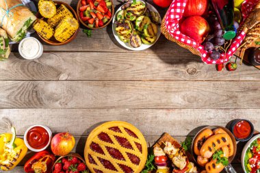 Çeşitli piknik barbekü yemekleri ve flatlay içiyorlar. Yaz bbq piknik yemekleri, ızgara etler, kebaplar, sebzeler, meyve salatası, geleneksel piknik pastası, sandviçler, üst görünüm fotokopi alanı.