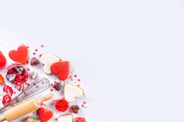 Valentine day baking background, Various bakery ingredients, cookies, chocolates, sugar sprinkles, strawberry, rolling pin and whisk, for cooking valentine`s sweets, desserts on white background