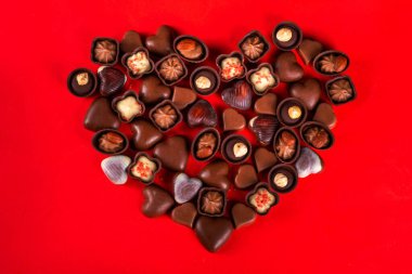 Valentines Day chocolates banner, background, frame. Various sweets and chocolate candy on red paper background with copy space. Romantic composition. Happy Valentine's day greeting card background