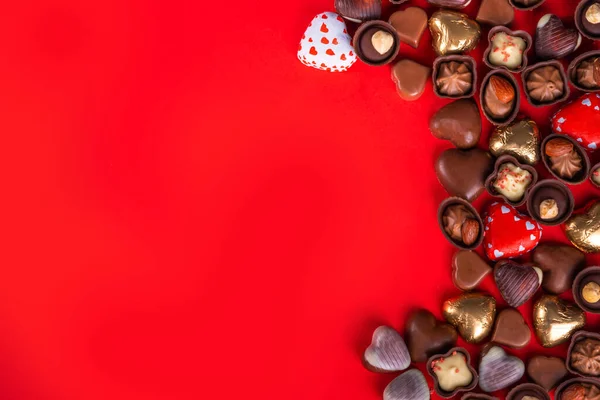 Valentines Day chocolates banner, background, frame. Various sweets and chocolate candy on red paper background with copy space. Romantic composition. Happy Valentine\'s day greeting card background