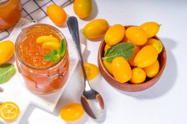 Kumquat jam, homemade citrus tropical fruit marmalade, with fresh kumquat on a white marble table
